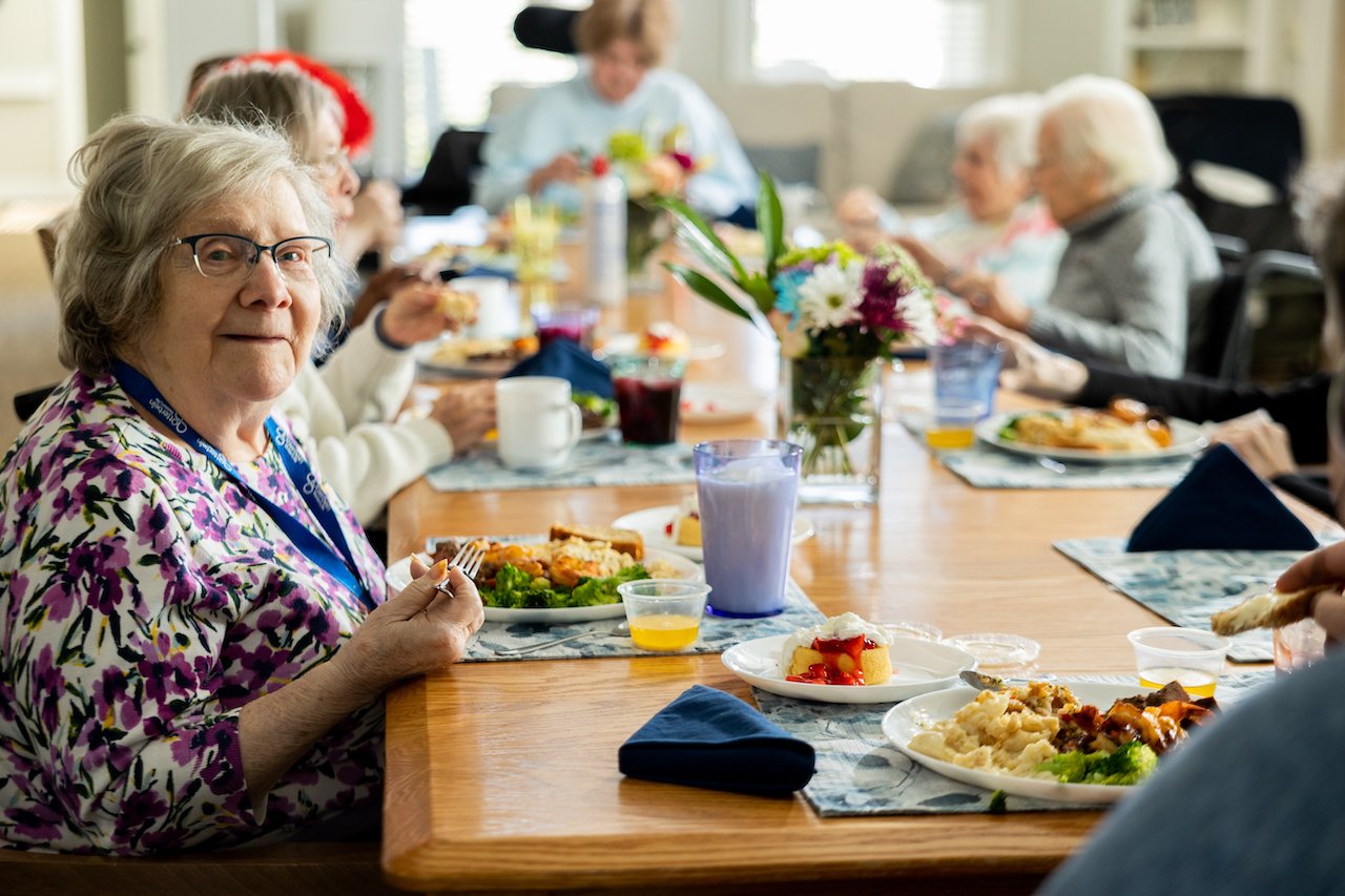 An elder enjoying a meal at the dining table with her fellow elders at an Otterbein SeniorLife Neighborhood.