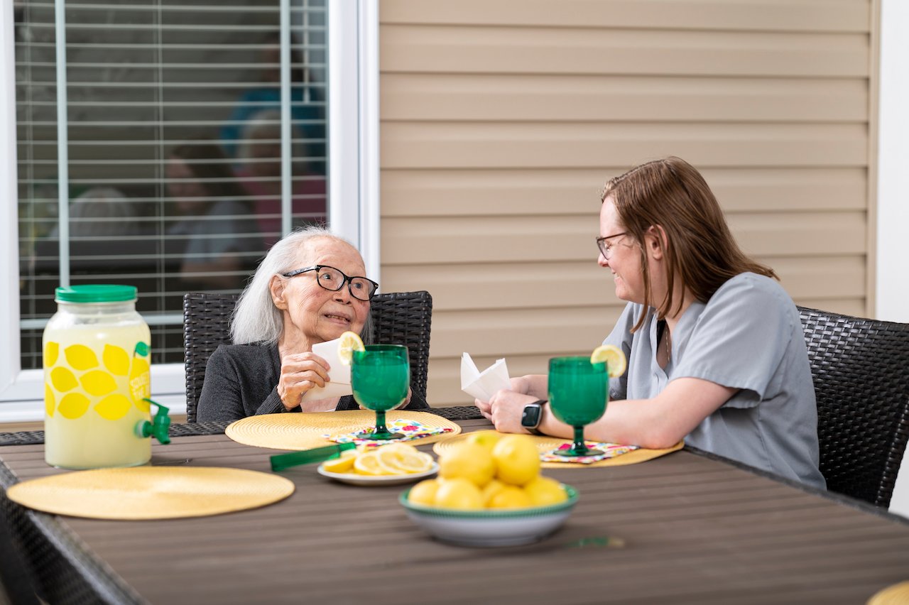 An elder and a partner drinking lemonade on the patio at an Otterbein SeniorLife Neighborhood.