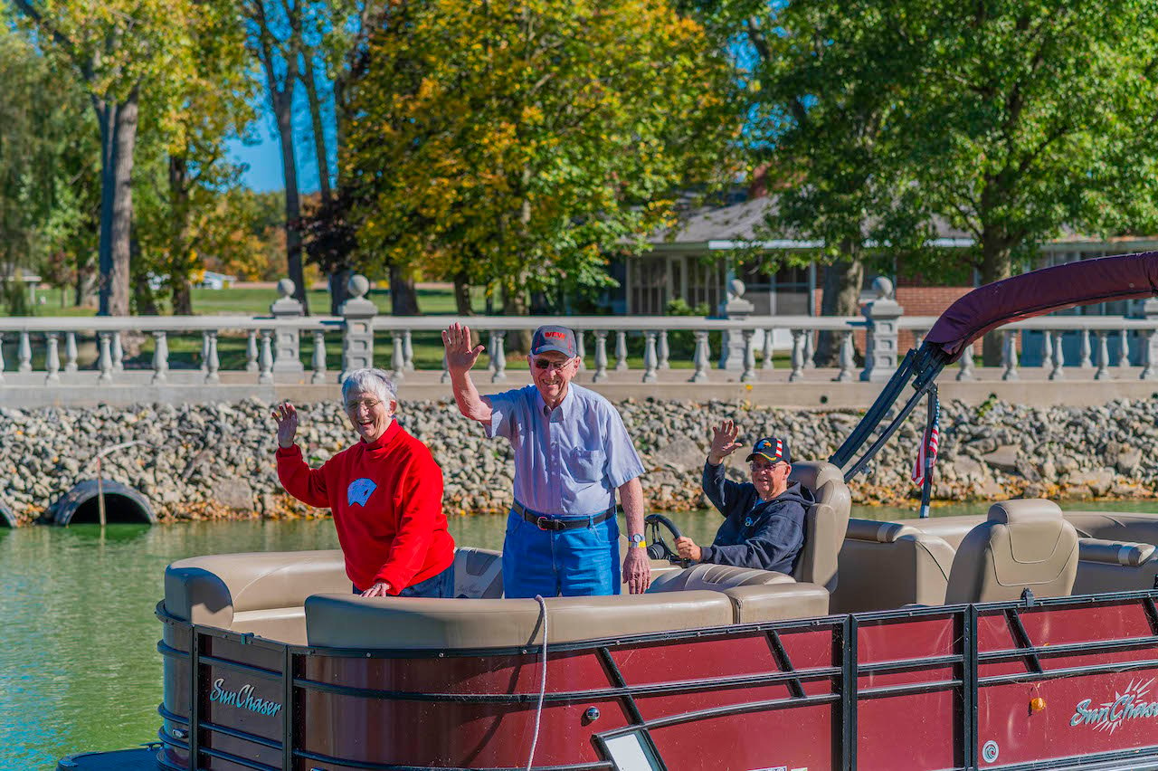 Otterbein St. Marys residents on a pontoon waving and smiling.