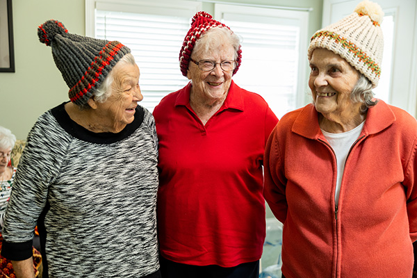 Otterbein Pemberville residents laughing together wearing hats they knitted.