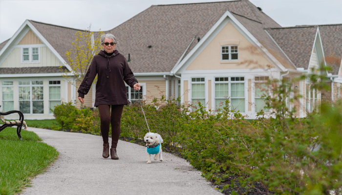 Senior woman spending time outside walking her dog.