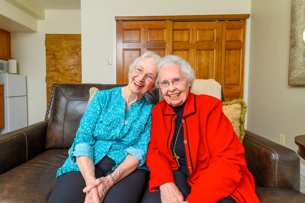Two senior women smile and spend time together in assisted living