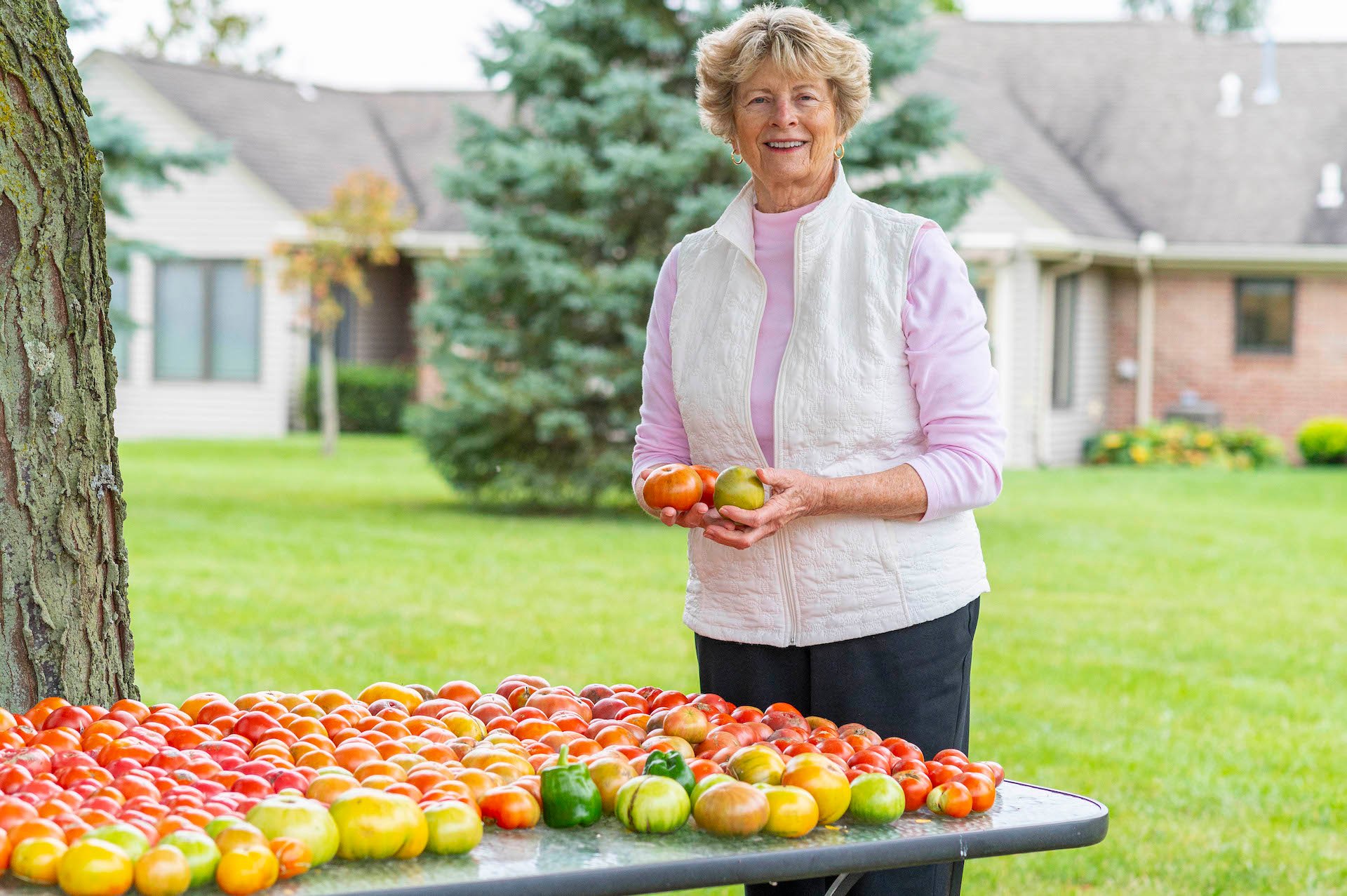Otterbein Pemberville resident, Cathy S., holding apples and smiling.