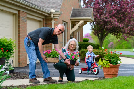 Retired couple planting flowers with grandson