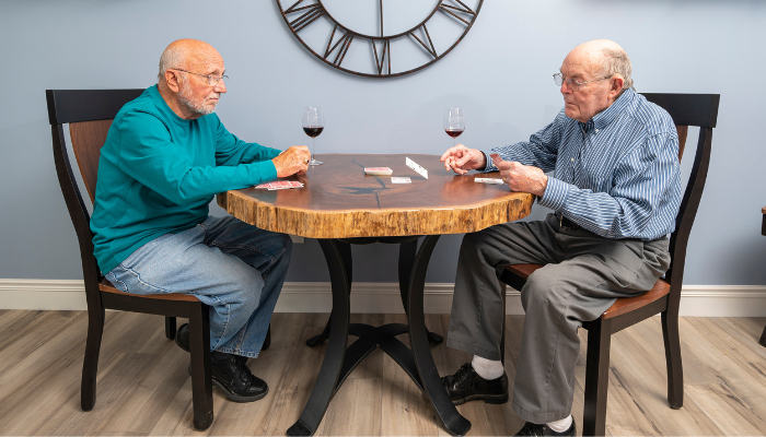 Carl and  another gentleman resident playing cards and enjoying a  glass of wine. 