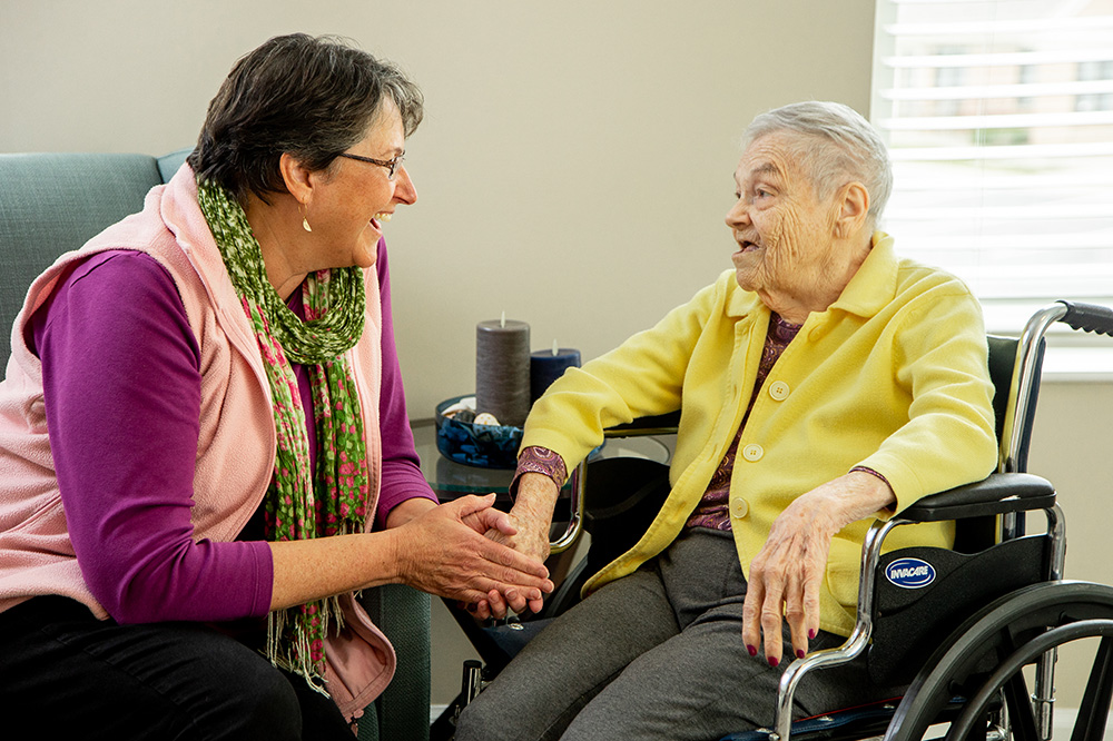 Caregiver talking with a senior woman that she helps care for.