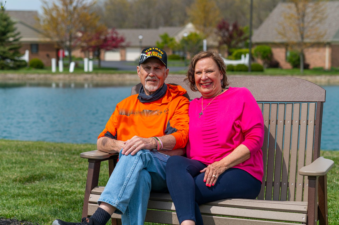 Otterbein Pemberville resident, Sue D., and her husband sitting on a bench and smiling.