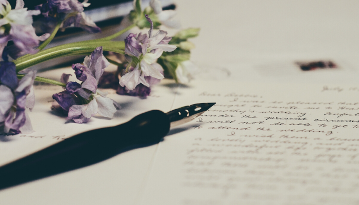  A pen and purple flowers laying on top of a handwritten note