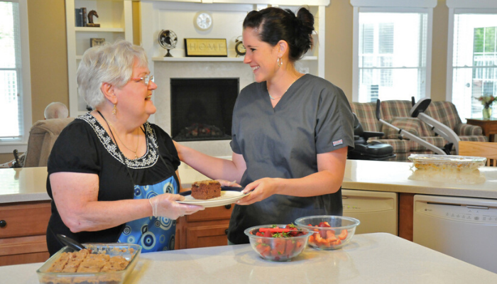  An Otterbein Marblehead Cornerstone Cottage staff member cooks with an elder in the small house kitchen