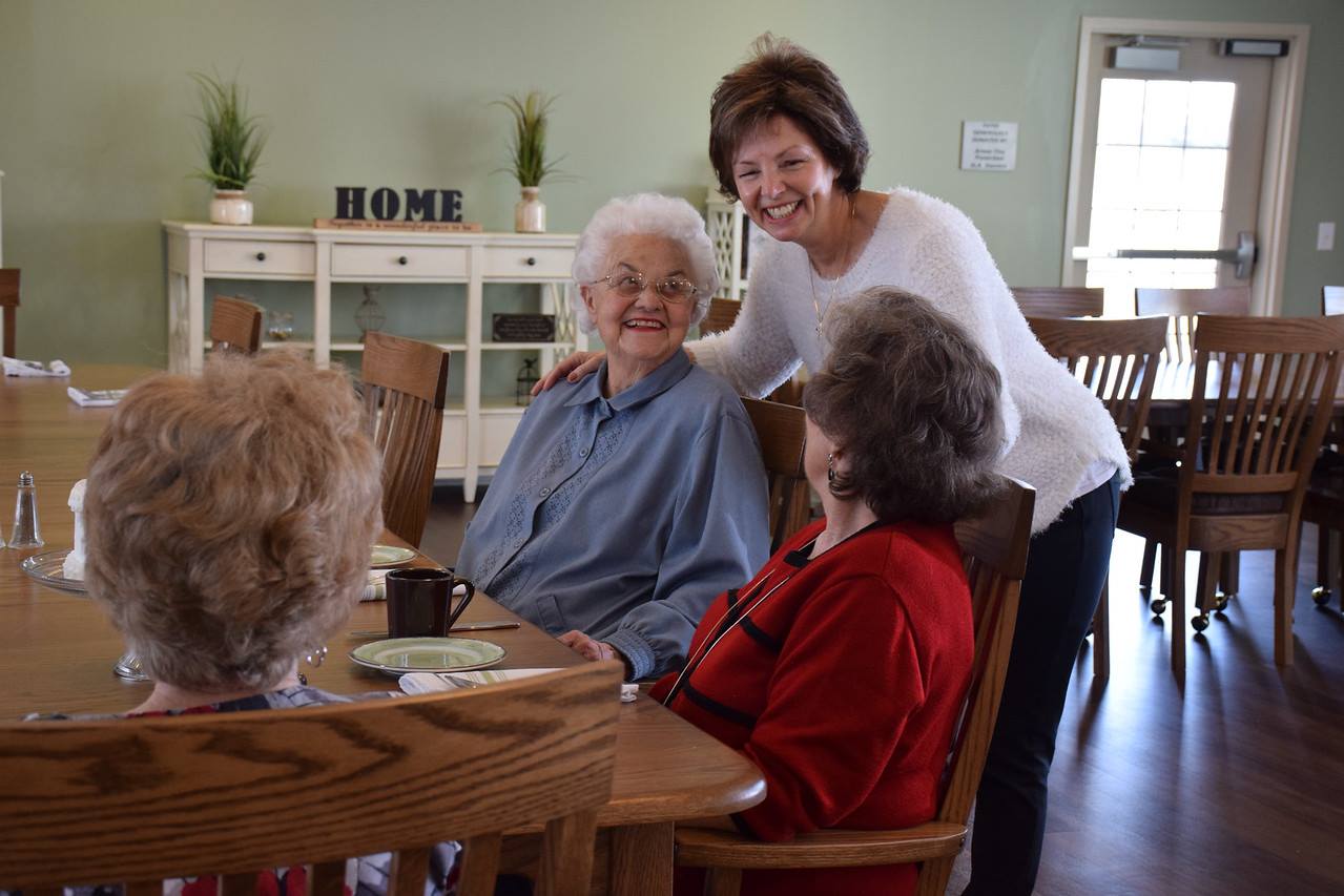 Residents being greeted by a partner at the dining table.