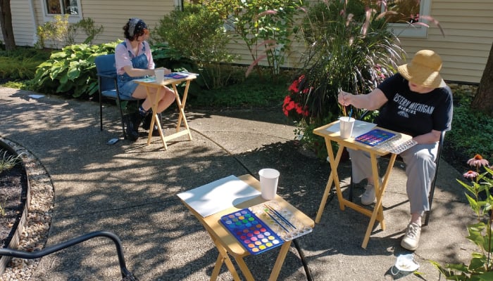 A Denison University artist-in-residence at Otterbein Granville leading residents in plein air painting, or open-air painting in The Courtyard.