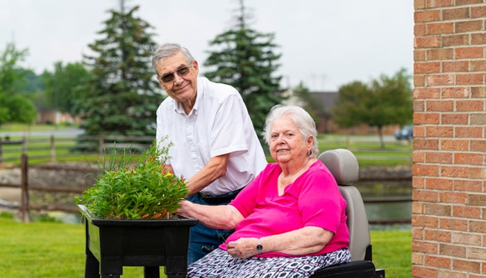 Otterbein Cridersville residents planting flowers in a raised flower bed outside of their home together