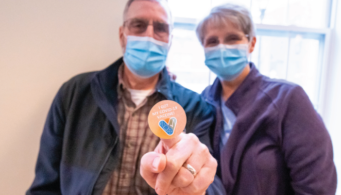 Two Otterbein Lebanon residents wearing face masks and showing a sticker saying that they received the COVID-19 vaccination promoting COVID safety at Otterbein SeniorLife
