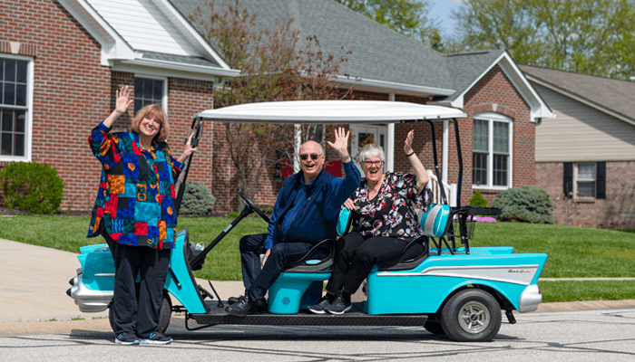 Otterbein Franklin residents riding in a golf cart while smiling and waving