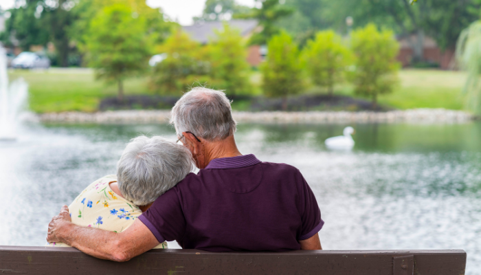 Couple sits on bench near pond 