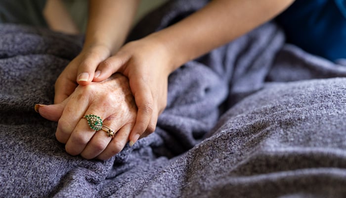 Caregiver holding the hand of a senior woman.