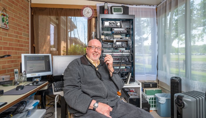 Otterbein Cridersville resident John W. sitting in his sunroom by his HAM radio.